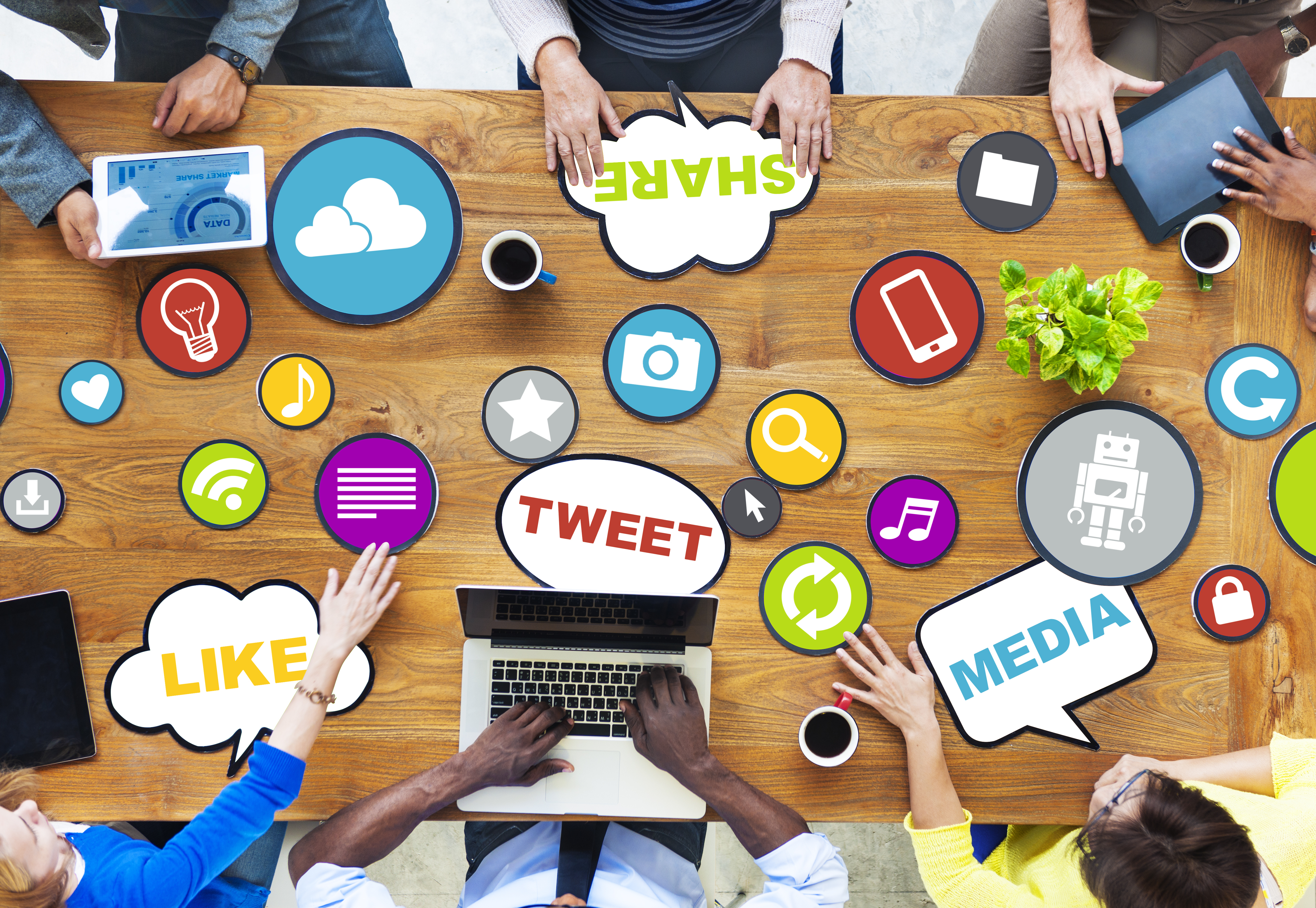 people sitting around a table with social media icons scattered on the table
